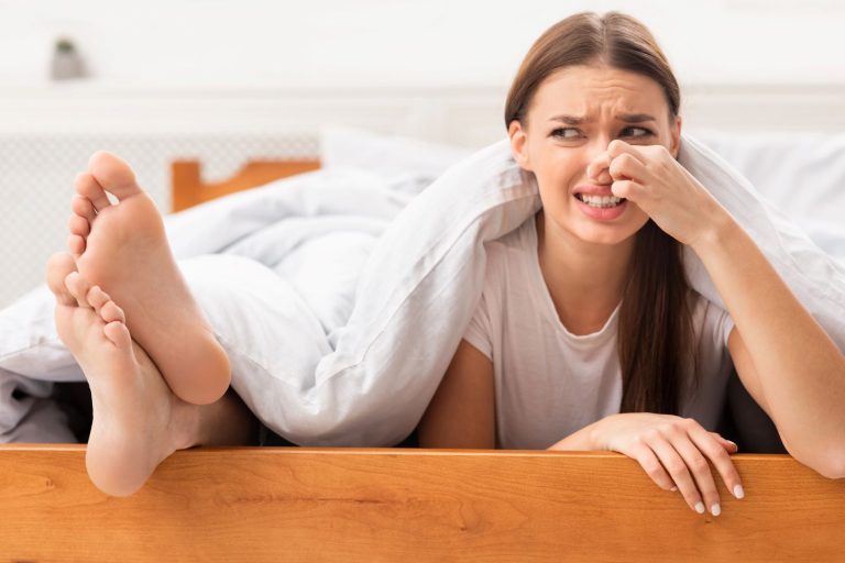 Stinky Feet, Disgusted girlfriend pinching nose lying near boyfriends smelly feet
