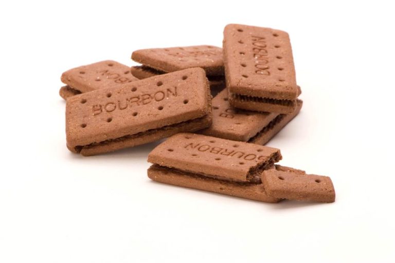 Pile of Bourbon biscuits, one broken, against a white background.