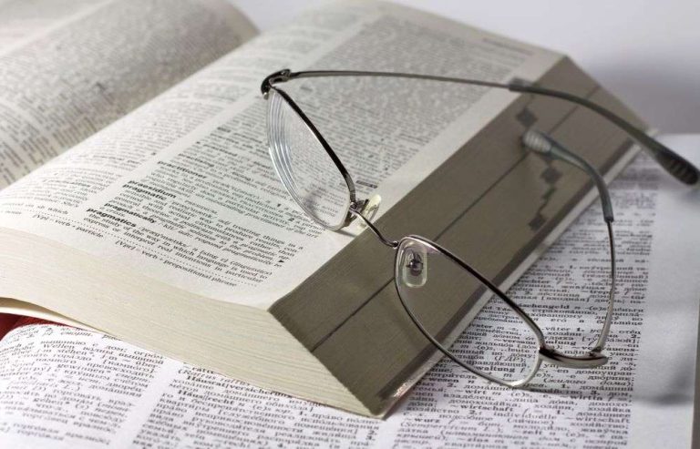 a pair of spectacles leaning against a large book