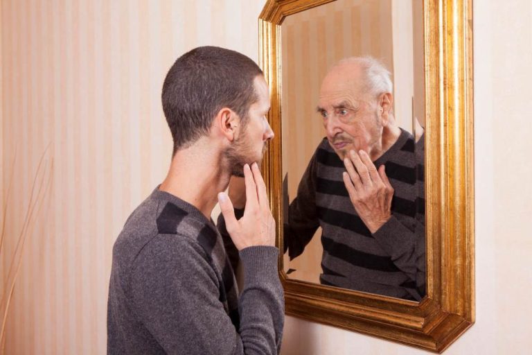 Young man looking in a mirror with an old man looking back in the reflection