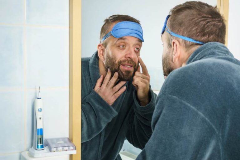 Middle aged man looking at his face in a mirror