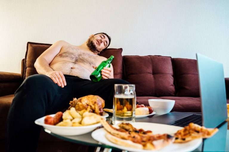 drunk man laying on sofa surrounded by takeaway food